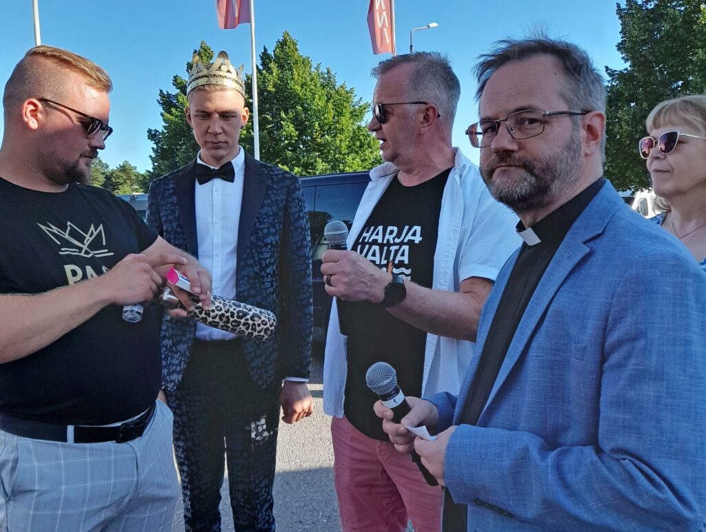 Kuvassa viisi ihmistä, puolikuvassa. Sininen taivas taustalla.